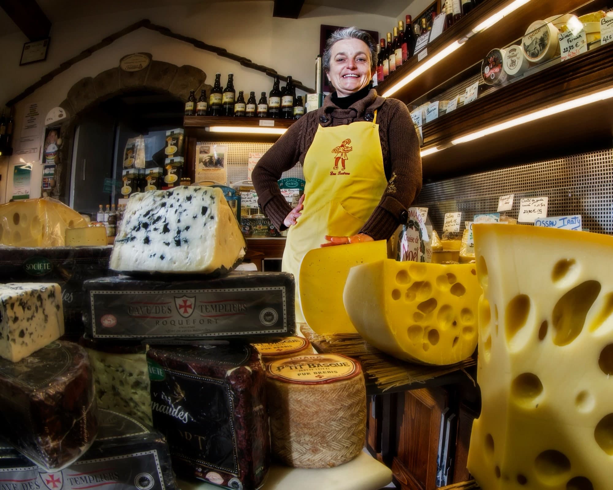 cremiere dans son magasin, entouré de morceaux de fromages
