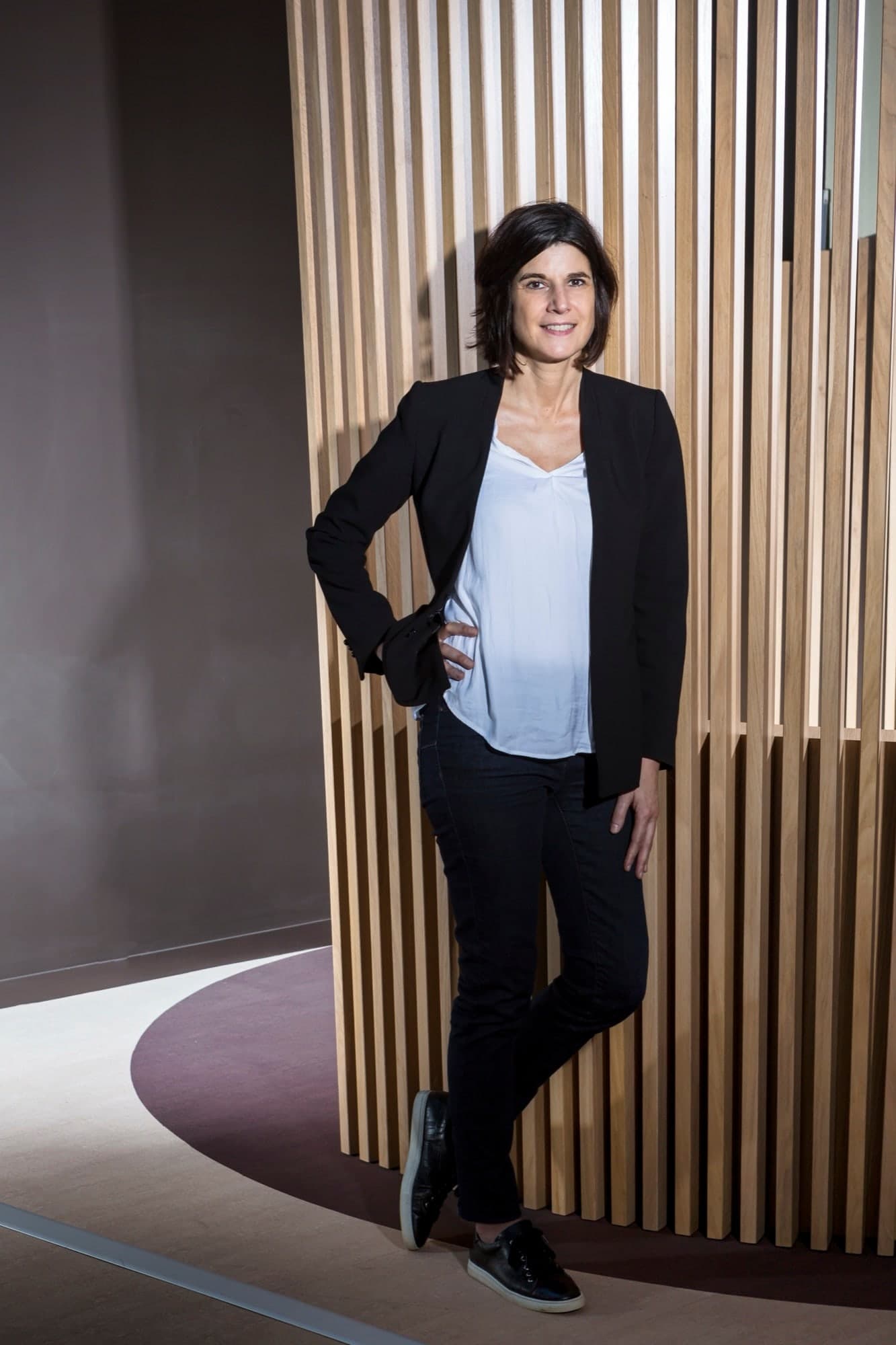 portrait d'une dirigeante de société, devant un mur en bois design