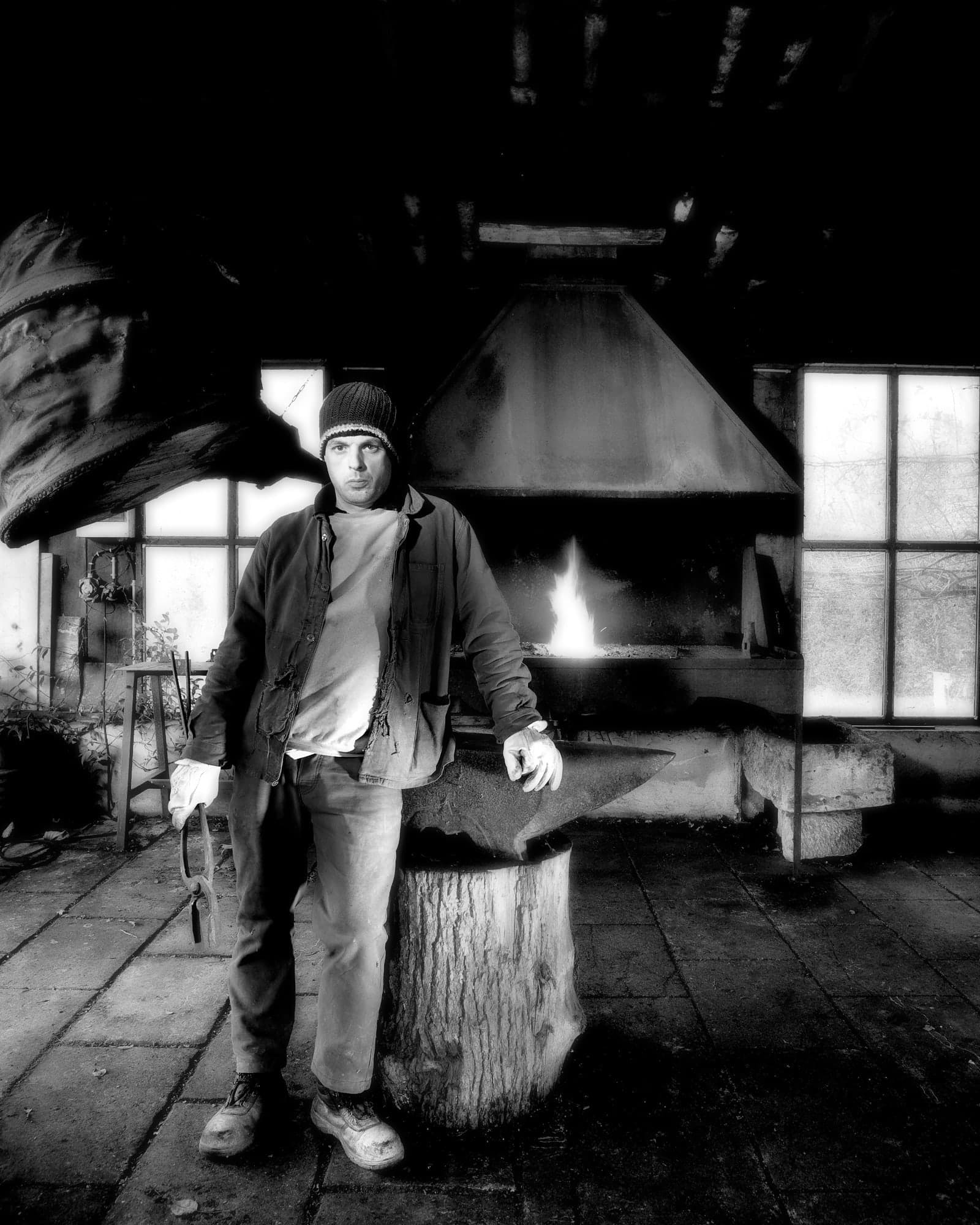 Artisan forgeron dans son atelier posant devant sa forge