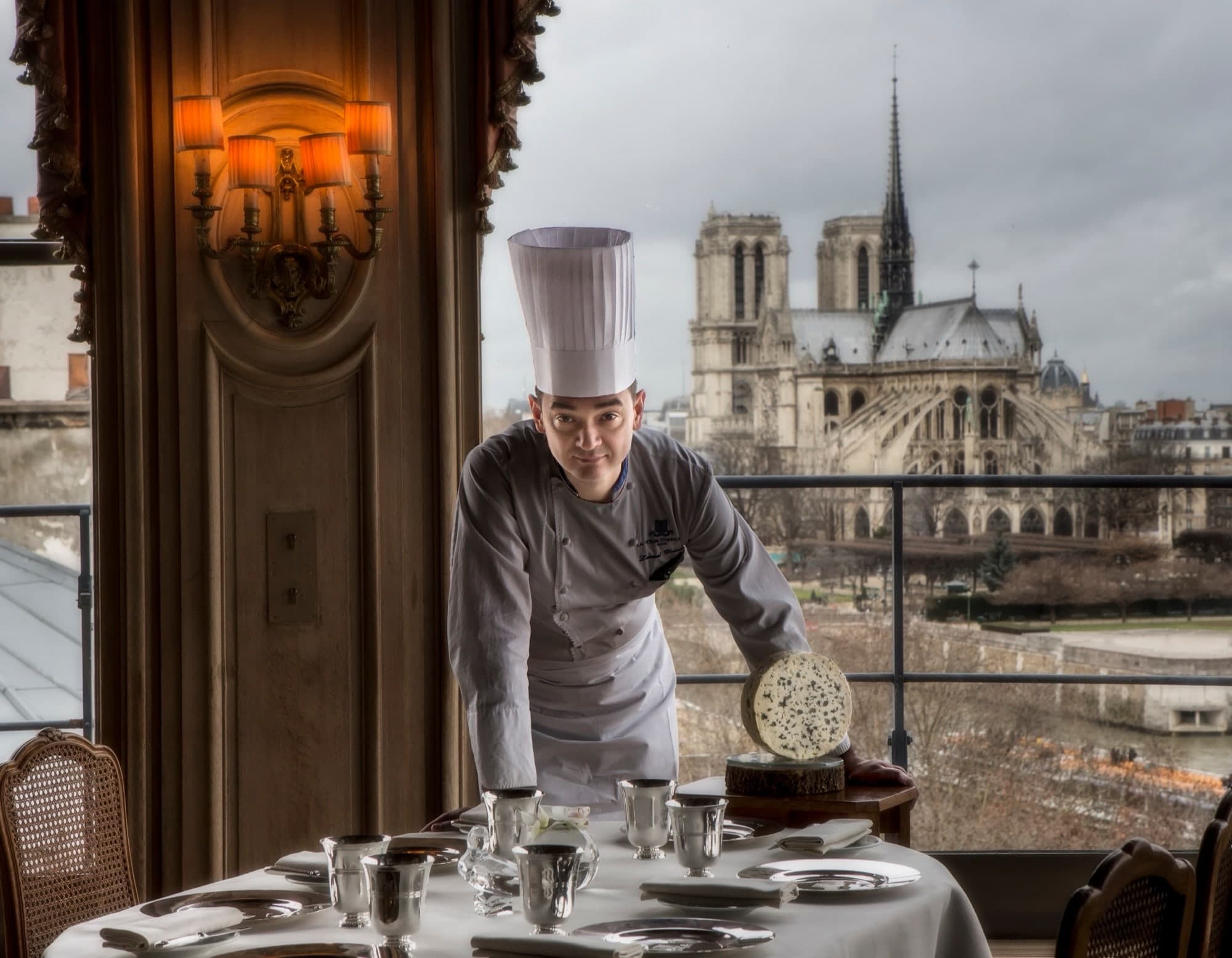 Portrait d'un chef dressant une table avec la cathédrale Notre-Dame en arrière-plan