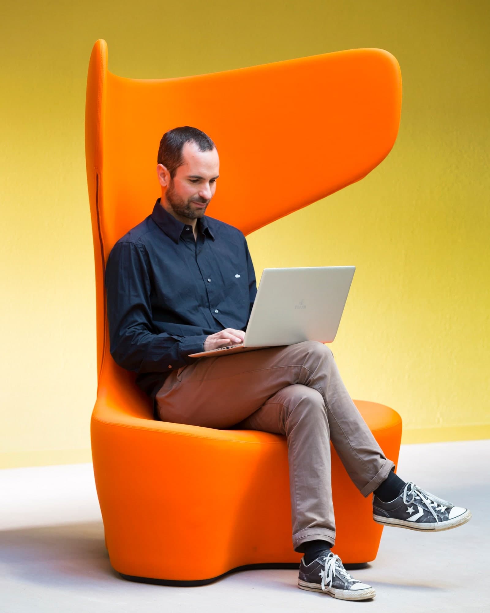 cadre d'une entreprise travaillant sur son ordinateur portable, assis sur un fauteuil design