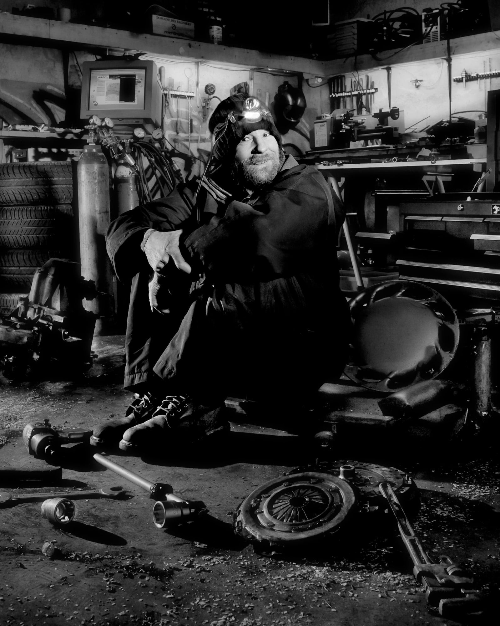 Mike H. dans son petit atelier-garage, au milieu de pièces détachés de véhicule